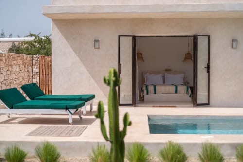 Chambre du Pavillon Belhazar avec mobilier moderne, fauteuils lounge verts et piscine privée au Domaine Belhazar à Essaouira