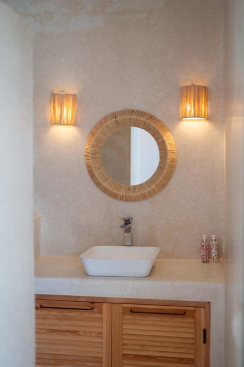 Salle de bains moderne au Domaine Belhazar avec miroir rond tressé, vasque et éclairage d'ambiance à Essaouira