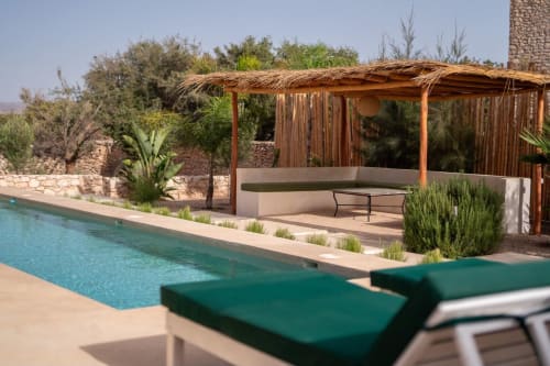 Élégante zone de piscine du Domaine Belhazar à Essaouira avec chaises longues, pergola en bois et jardins méditerranéens