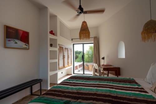 Chambre spacieuse à Domaine Belhazar, Essaouira avec literie rayée verte, luminaires tissés suspendus et vue océan