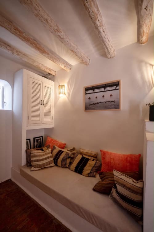 Coin de lecture douillet avec poutres apparentes, coussins et éclairage chaleureux au gîte Domaine Belhazar à Essaouira