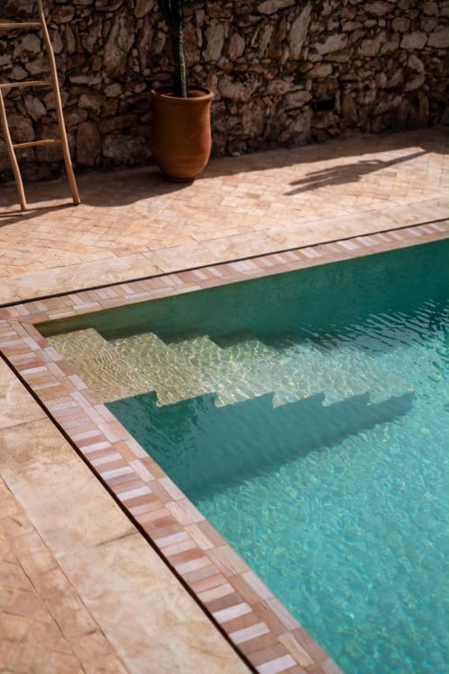 Piscine turquoise aux carrelages et reflets d'ombres au Domaine Belhazar, maison d'hôtes avec patio en terre cuite