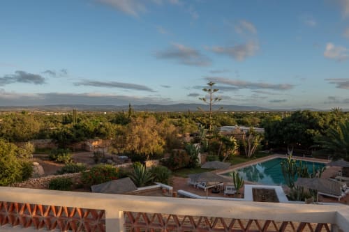 Piscine du Domaine Belhazar surplombant les jardins d'Essaouira au coucher du soleil, eaux turquoise entourées d'un paysagisme désertique