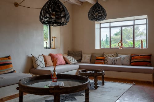 Spacieux salon du cottage Domaine Belhazar à Essaouira avec sièges confortables, table ronde en bois et suspension tressée noire