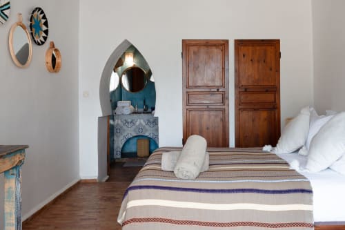Chambre marocaine rustique à Domaine Belhazar à Essaouira avec portes en bois, vasque en arche et literie rayée