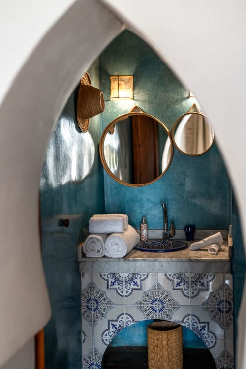 Alcôve salle de bain marocaine voûtée au Domaine Belhazar, Essaouira avec murs bleu-vert, miroirs ronds et carrelage bleu décoratif
