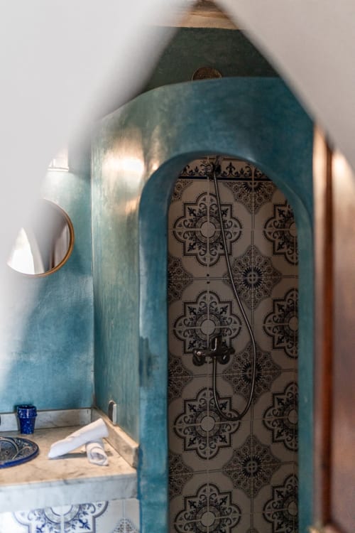 Salle de bain marocaine aux murs turquoise, porte cintrée décorée de zellige au Domaine Belhazar, Essaouira