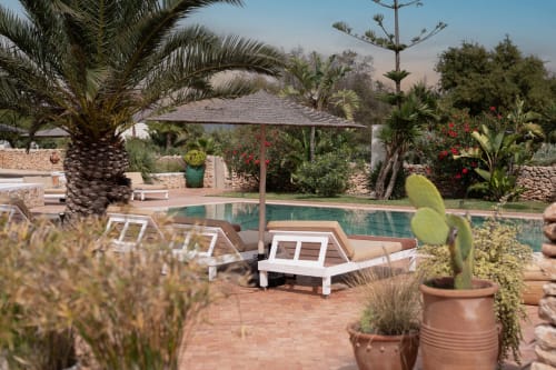 Espace piscine du Domaine Belhazar à Essaouira avec transats, palmiers et architecture en pierre