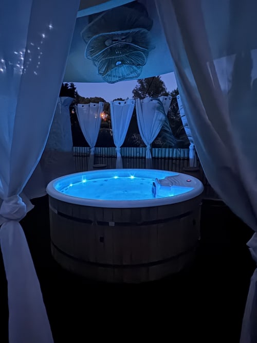 Jacuzzi rond illuminé aux néons bleus sur la terrasse du Mas Aurel de Provence, Peypin, drapé de rideaux blancs