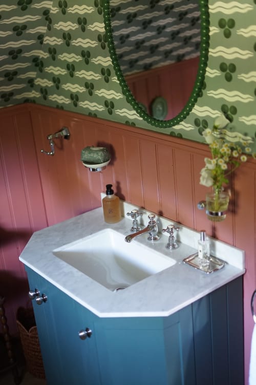 Salle de bain Meadow Room de La Roquerie avec vasque bleu, plan de travail en marbre blanc, papier peint cactus et terre cuite
