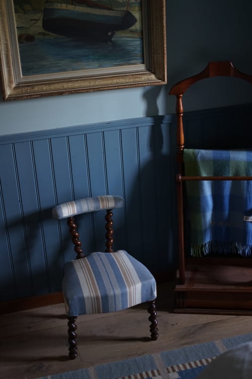 Chaise rayée bleue dans la Paddock Room de la Ferme La Roquerie à Bonneville-la-Louvet, avec tableau de lac et boiseries