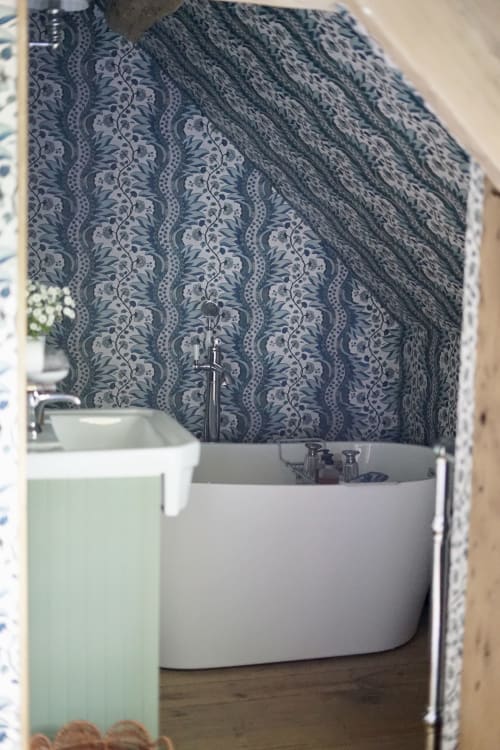 Baignoire moderne ronde avec papier peint bleu damassé dans la chambre Paddock à La Roquerie, maison d'hôtes en France