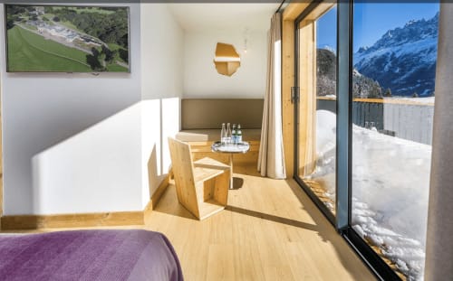 Deluxe bedroom at Le Chalet Mont-Blanc with mountain views, wooden furnishings, and snowy Alps visible through large windows