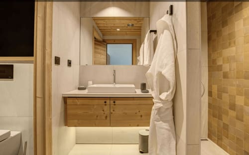 Modern bathroom at Le Chalet Mont-Blanc with wooden vanity, vessel sink, large mirror, and gold-tiled shower area