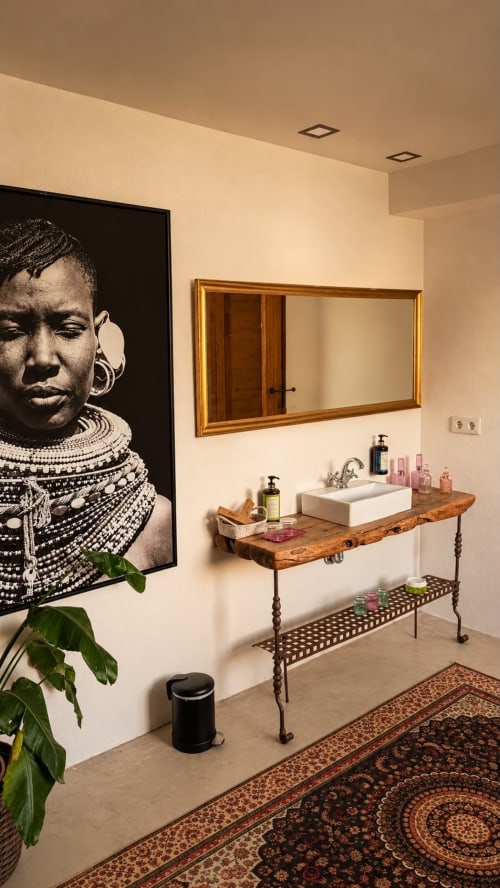 Stylish bathroom at Finca Almenara De Copau with wooden vanity, white vessel sink, and African portrait art