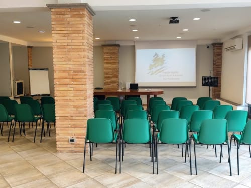 Sala conferenze con sedie verdi e schermo di proiezione al Green Hotel Poggio Regillo di Frascati