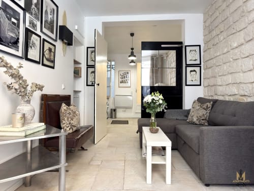 Modern Paris apartment living room with gray sofa, brick wall, and kitchenette at Montmartre Apartments