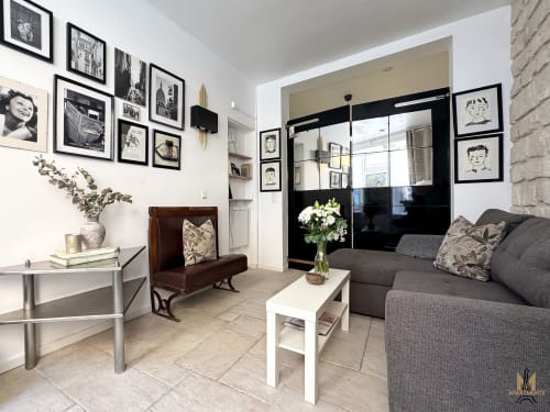 Stylish Paris apartment living room with gray sofa, framed art gallery wall, and modern black mirror at Montmartre Apartments
