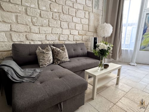Modern living room in Montmartre Apartments Paris with gray sectional sofa, white brick wall, and city views