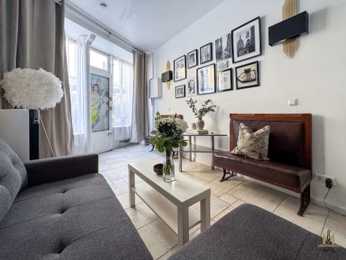 Androuet Atelier apartment in Montmartre, Paris - modern living room with gray sofa, wooden bench, gallery wall, and