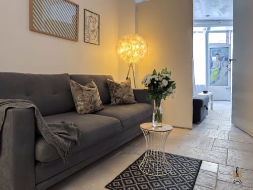 Modern living room at Montmartre Apartments Paris with dark sofa, pendant lamp, and fresh flowers