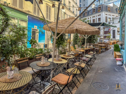 Charming Parisian courtyard café with tables, wicker umbrellas, and ivy-covered buildings in Montmartre, Paris