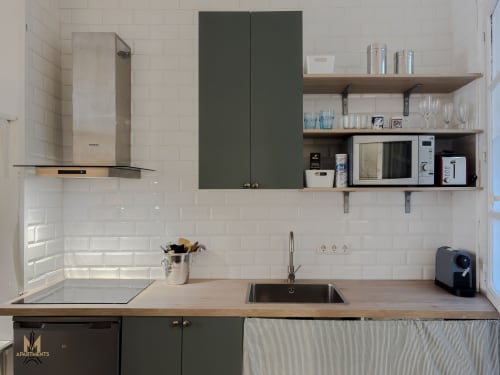 Modern kitchenette in Montmartre Apartments Paris with white subway tiles, dark cabinetry, wood countertops, open shelving,