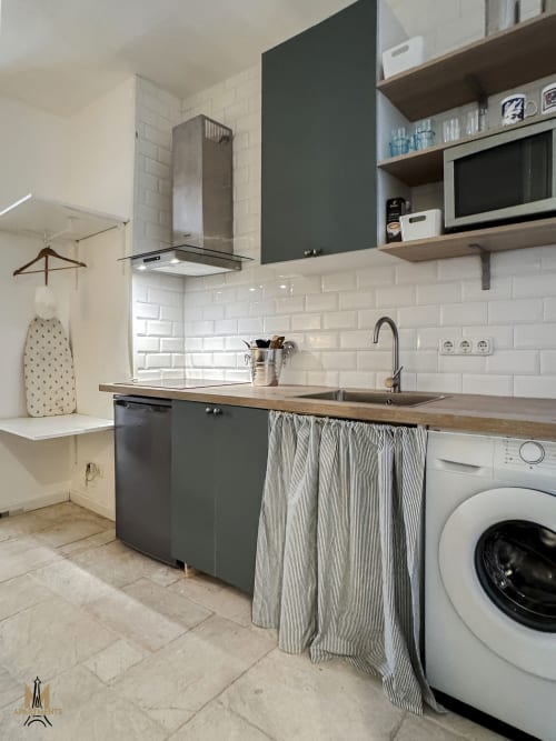 Modern kitchen in Montmartre Apartments Paris with dark green cabinets, white subway tile, stainless steel sink, and
