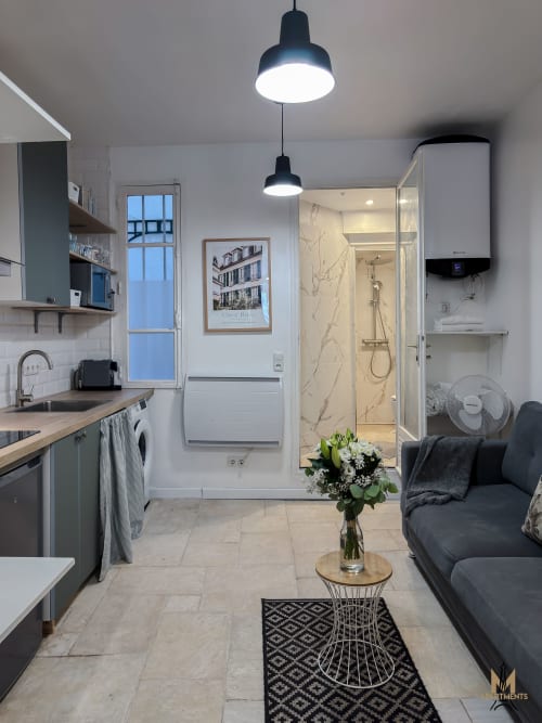 Modern Parisian studio at Montmartre Apartments with open-plan kitchen, bathroom, living area, pendant lighting, and marble