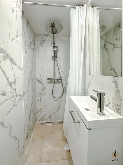 Modern bathroom in Montmartre Apartments Paris with marble-effect tiles, walk-in shower, white sink vanity, and chrome