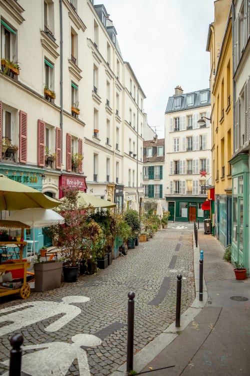 Charming Parisian street in Montmartre with colorful storefronts, outdoor café seating, and historic apartments