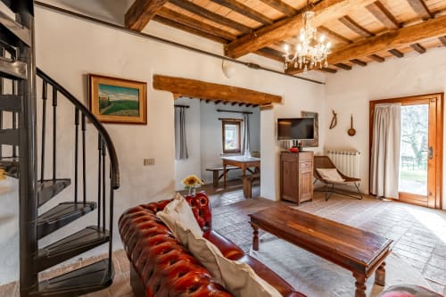 Sala da pranzo rustica toscana con travi a vista, divano in pelle rossa e mobili in legno dell'hotel Quarantallina a Buonconvento