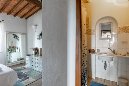 Bagno della camera Cipresso con piastrelle bianche, lavabo, specchio e dettagli blu presso l'Hotel Quarantallina, Buonconvento