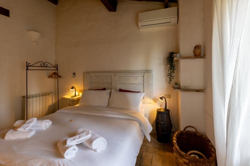 Camera Cipresso dell'hotel Quarantallina a Buonconvento con biancheria bianca, luci soffuse e muri in pietra rustica