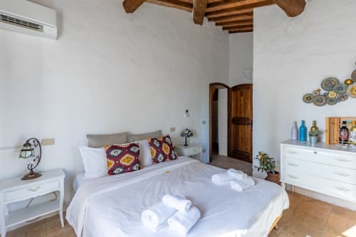 Spaciosa camera nella stanza Olmo dell'hotel Quarantallina a Buonconvento, Italia, con biancheria bianca, travi in legno e vista sulla campagna