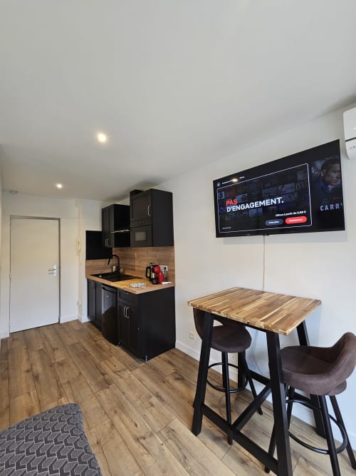 Cuisine et salle à manger Studio Mirabeau 2 aux Lodges de Barbieux, Croix : mobilier noir, table en bois et télévision