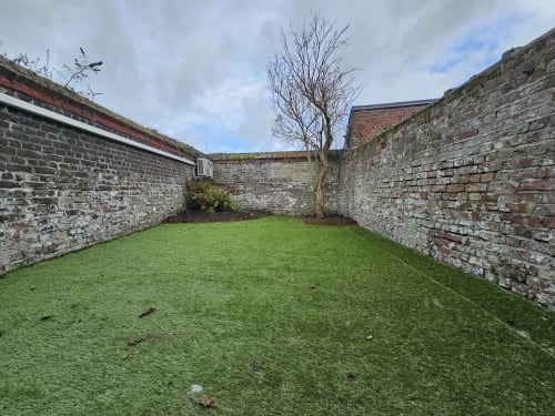 Jardin privé clôturé avec pelouse verdoyante et murs en pierre aux Lodges de Barbieux, Croix