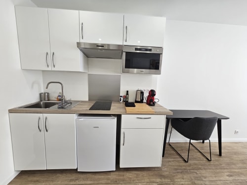 Cuisine moderne aux placards blancs, électroménagers inox et coin repas dans l'appartement Studio Mirabeau 1 des Lodges