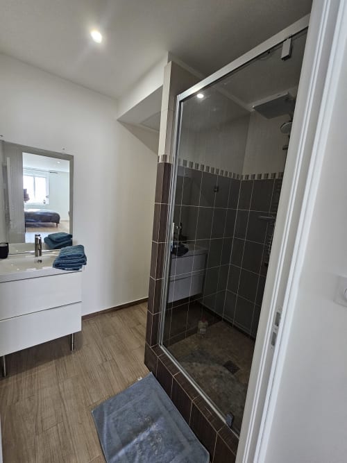 Salle de bains moderne avec douche en carrelage noir, vasque blanche et miroir à Les Lodges de Barbieux à Croix