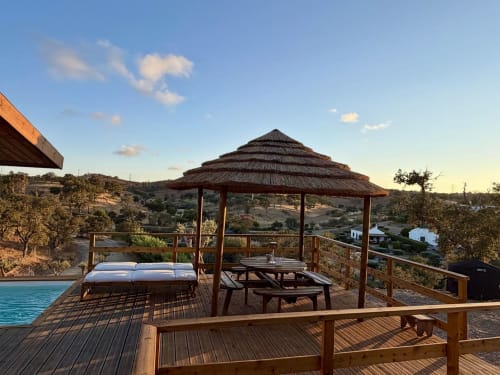 Terraço em madeira com gazebo, zona de repouso e piscina na quinta Casa do Montado em Almodôvar, Portugal, com vistas para o campo