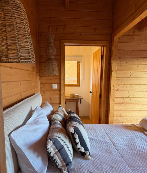 Quarto aconchegante com móveis de madeira na vila Corvatos Casas do Monte em Almodôvar, com roupas de cama brancas e almofadas listradas