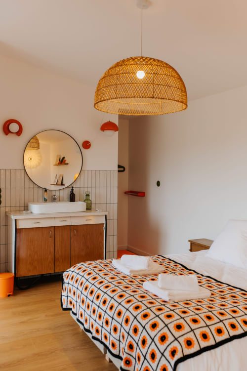 Chambre de cottage moderne avec lampe suspendue tressée, coiffeuse en bois, miroir rond, linge de lit à motifs, Landunvez Bretagne