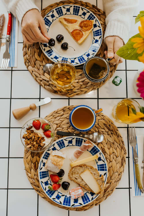 Vue aérienne d'un petit-déjeuner champêtre français avec fromage, pain, pâtisseries, fruits rouges, café et thé aux écuries du