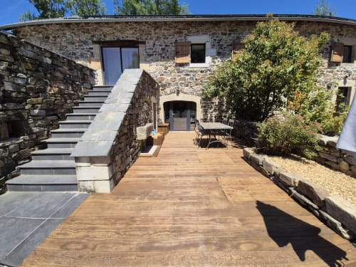 Entrée du gîte en pierre avec terrasse en bois aux Pays des Sucs, Saint-Hostien. Coin détente dans le jardin.