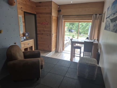 Chambre double moderne aux Pays Des Sucs B&B à Saint-Hostien avec murs en bois, fauteuils marron et portes-fenêtres donnant sur