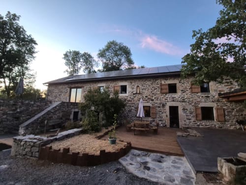 Cour pavée de pierre de la maison d'hôtes Aux Pays Des Sucs à Saint-Hostien avec terrasse et panneaux solaires