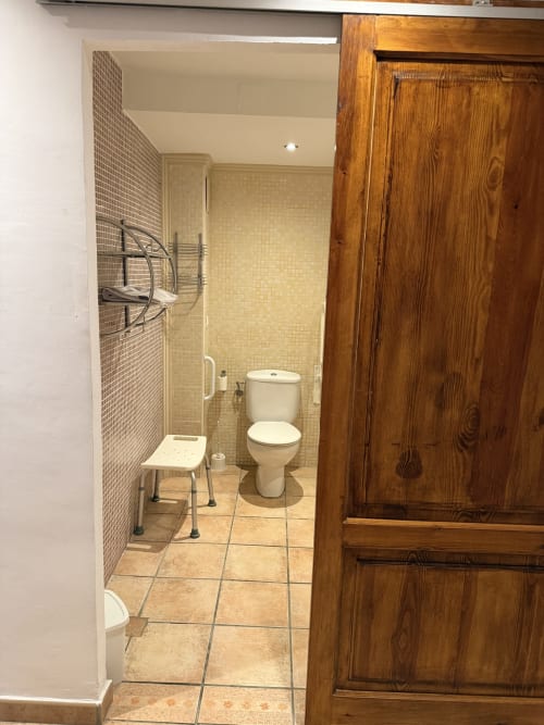 Baño accesible en Hotelito Oliva Pensión con ducha sin escalón, inodoro y barras de apoyo en Oliva, España