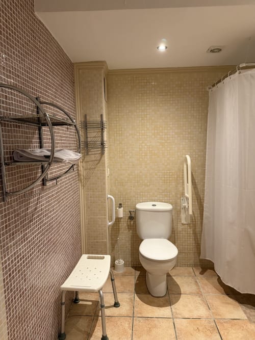 Baño accesible en Hotelito Oliva Pensión con inodoro, ducha, barras de sujeción y ayudas para la movilidad en Oliva, España