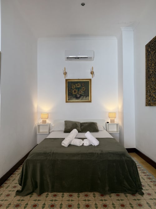 Elegante habitación doble en Hotelito Oliva Pensión en Oliva con ropa de cama verde, mesitas blancas, apliques dorados y aire