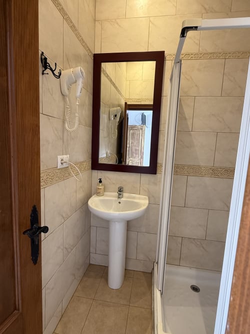Baño moderno de Hotelito Oliva Pensión con lavabo pedestal, espejo enmarcado, secador de pelo mural y cabina de ducha